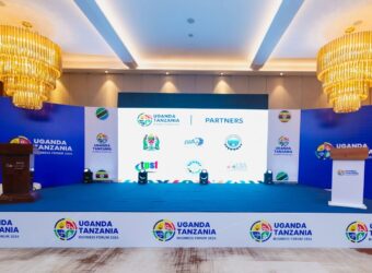 Large LED screen displaying branded visuals of the Uganda-Tanzania Business Forum during a presentation session, designed by Mbembo.