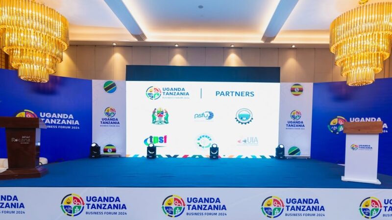 Large LED screen displaying branded visuals of the Uganda-Tanzania Business Forum during a presentation session, designed by Mbembo.